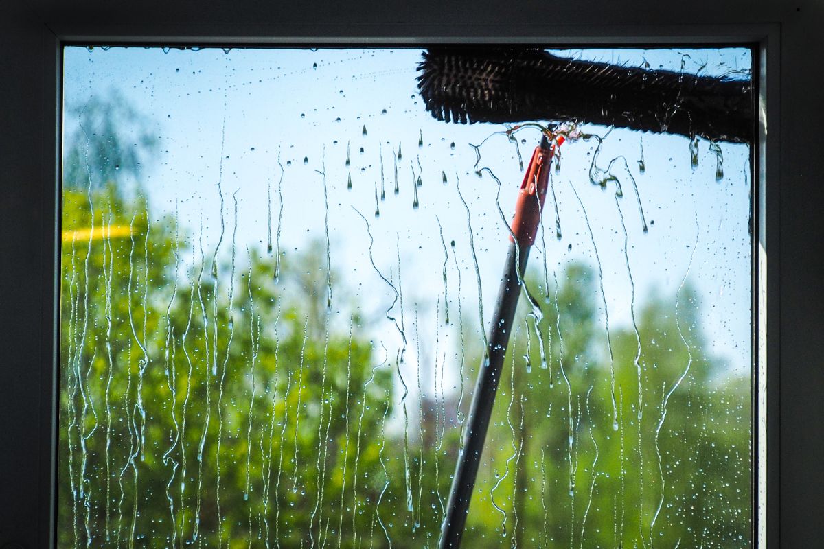  A professional window cleaner applying cleaning tools to a window, highlighting the process of achieving a spotless finish.